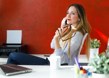 Beautiful young woman using her mobile phone in the office.